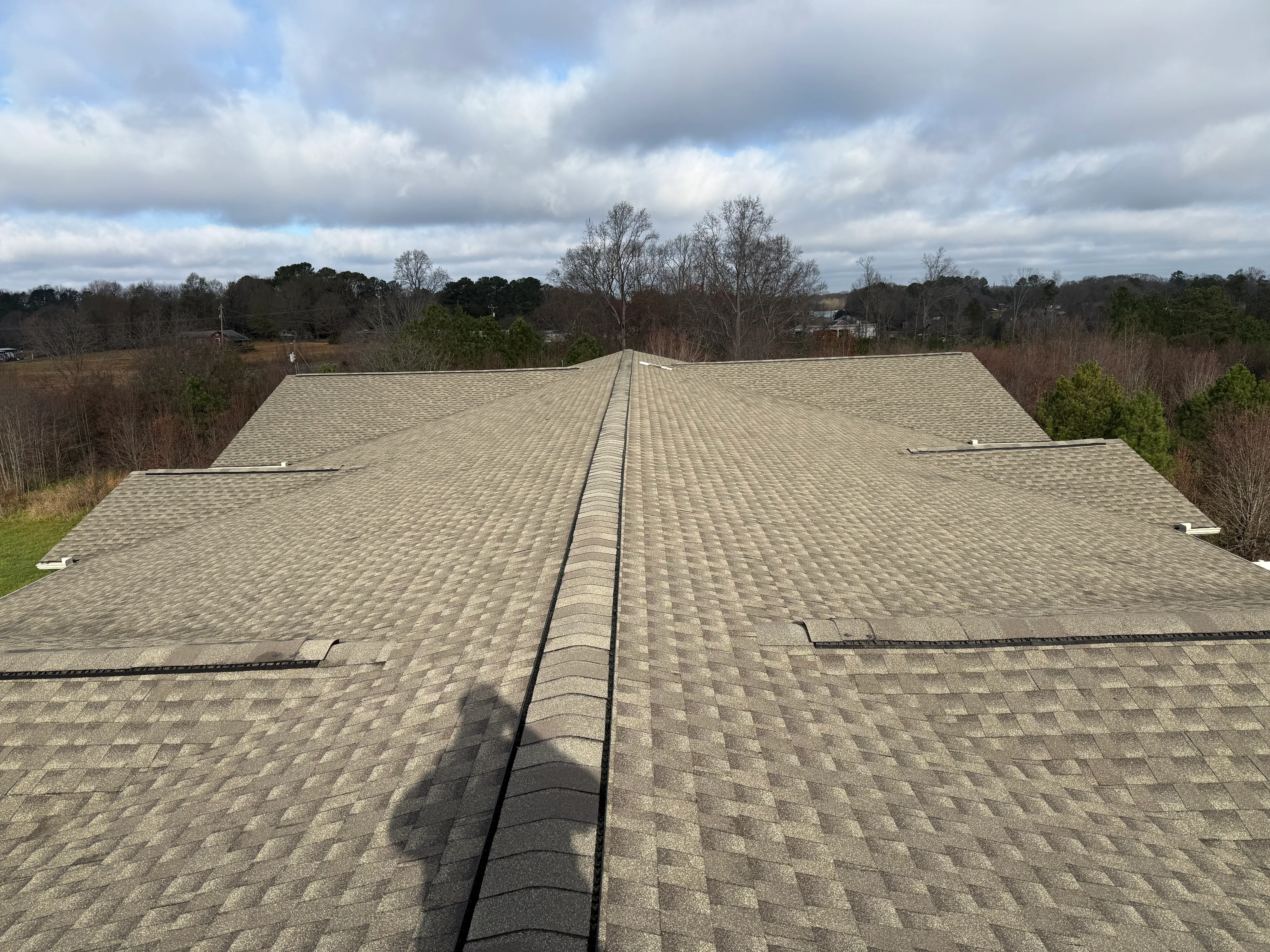 Newly installed tan architectural shingle roof with ridge cap on residential home in Shelby