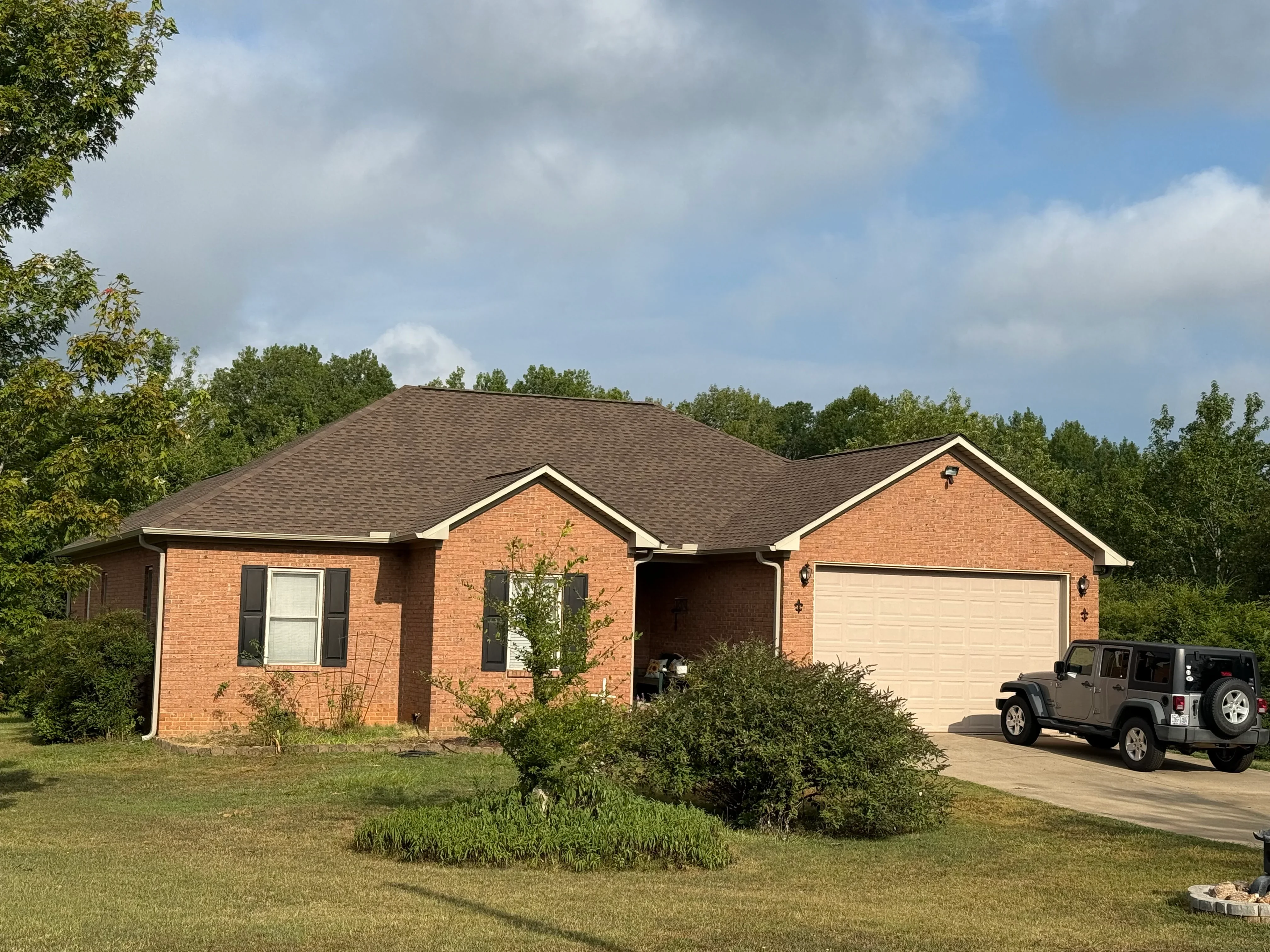 Brick ranch home with newly installed charcoal gray asphalt shingle roof and white trim