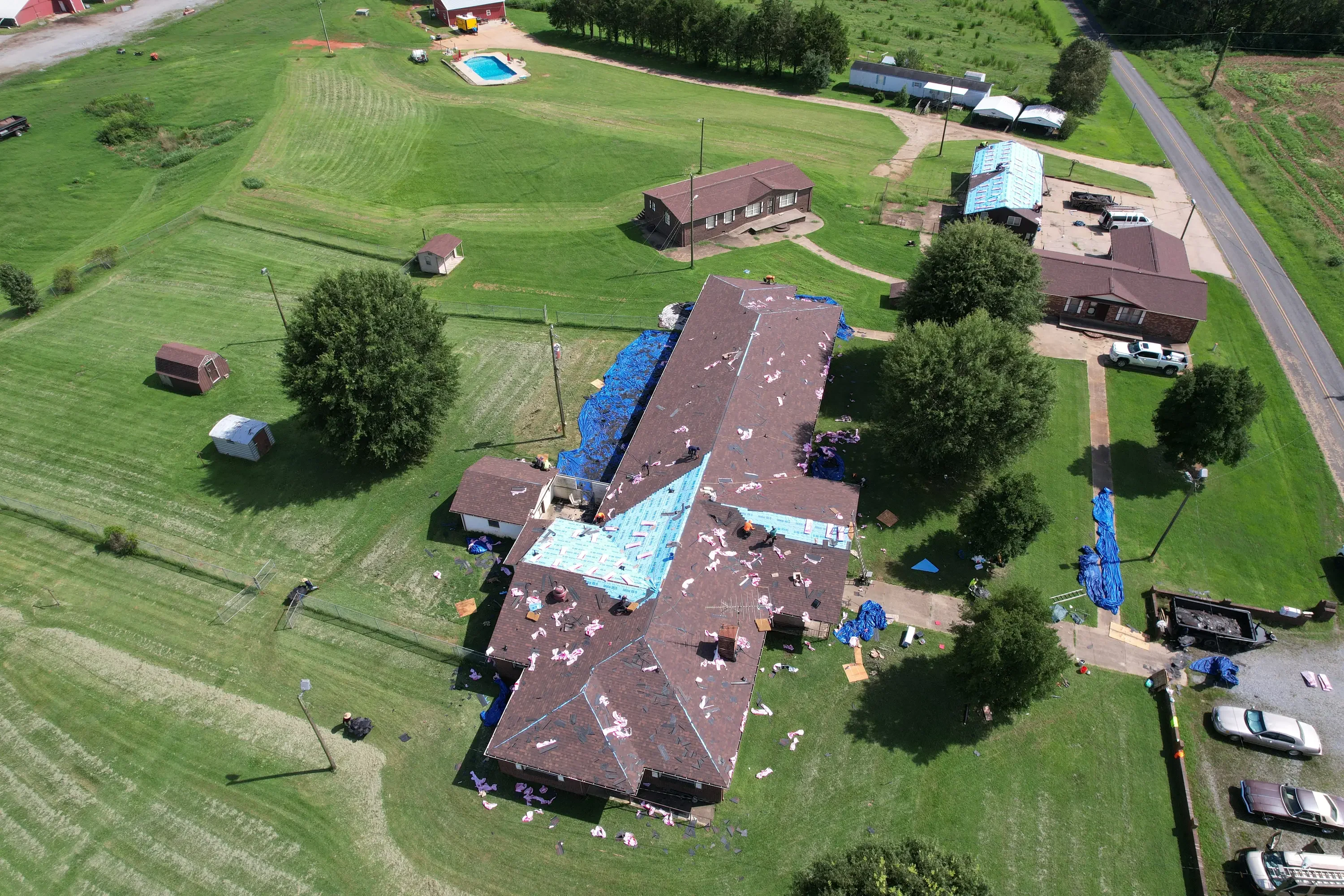 Aerial view of residential roof replacement in progress with blue tarping and new shingles