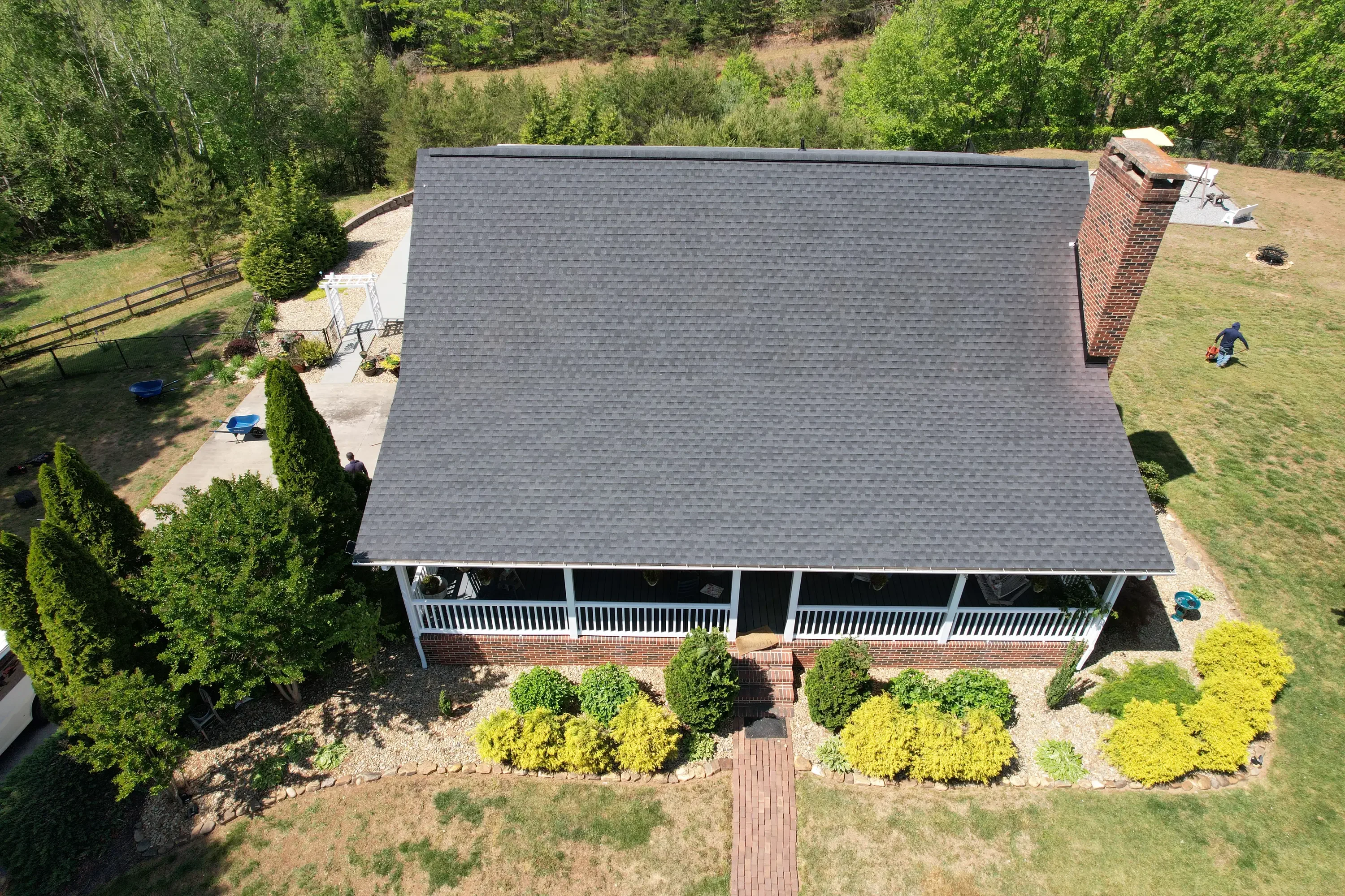 Aerial view of completed residential roof with gray architectural shingles on brick home