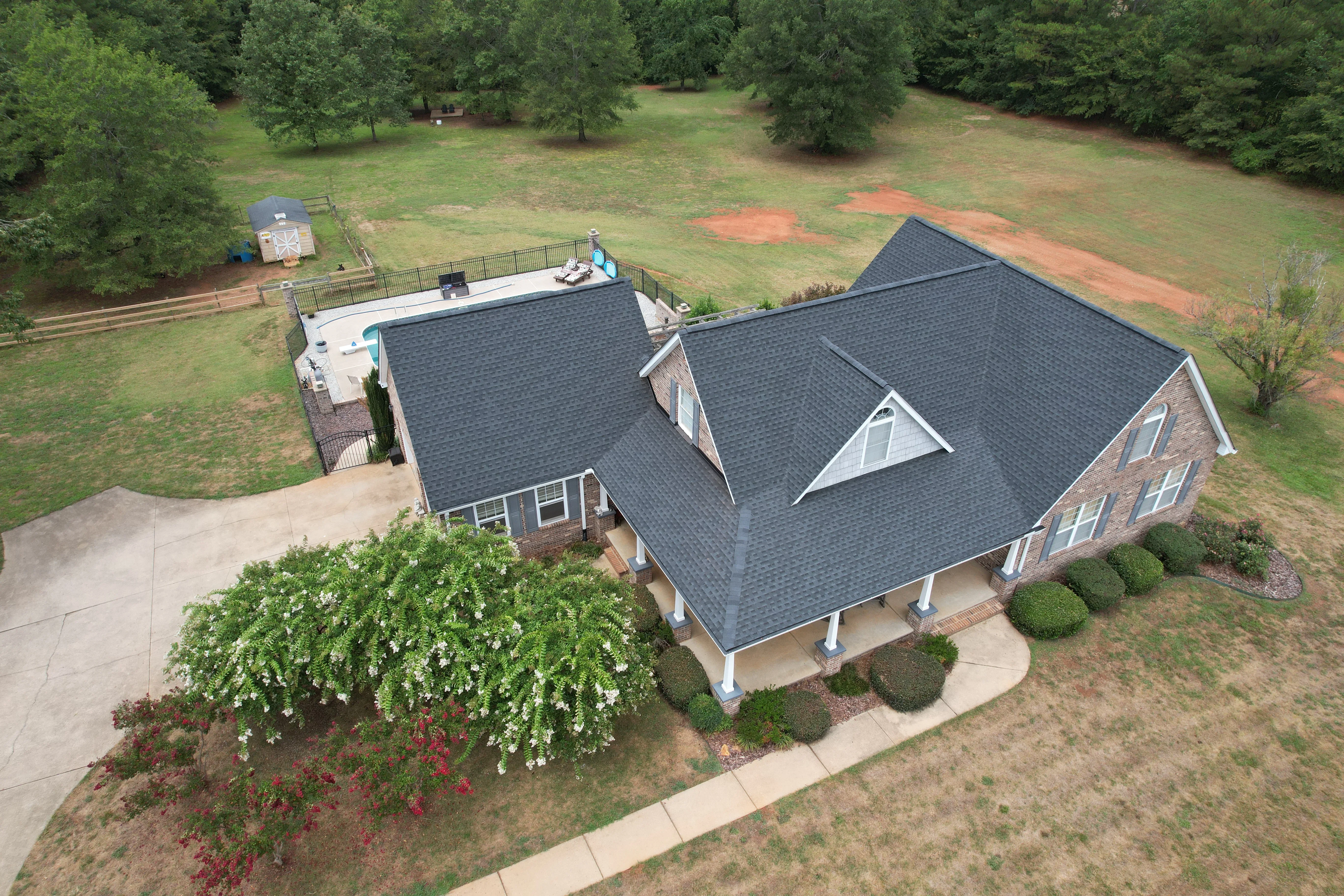 Aerial view of brick home with new dark architectural shingle roof and white trim
