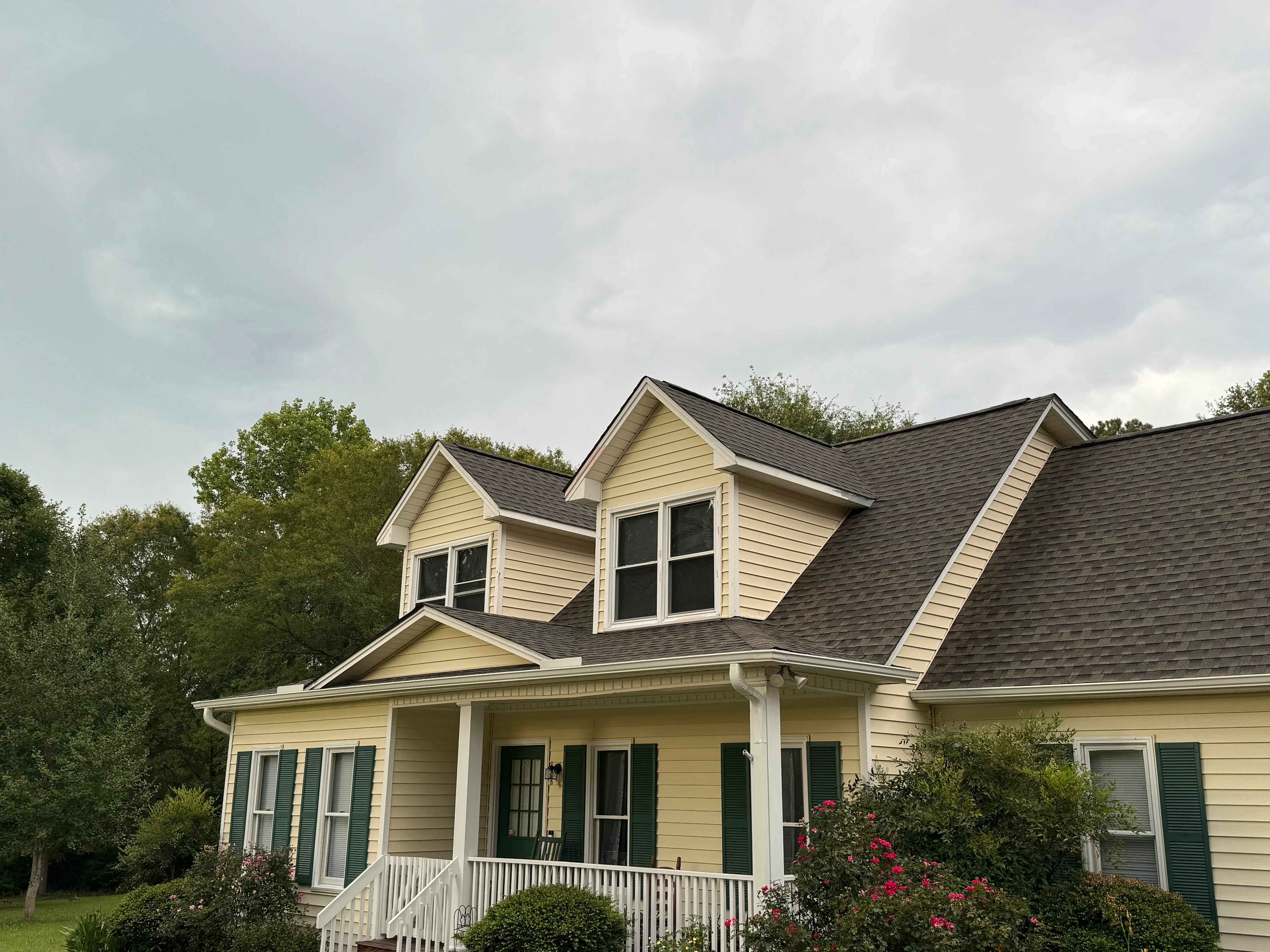 Two-story home with new charcoal gray asphalt shingle roof and white front porch
